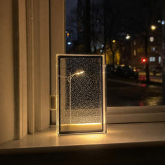 Lámpara de nieve con farola en miniatura iluminada junto a una ventana de noche